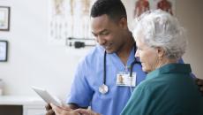 Healthcare provider and a patient standing next to each other both looking at a tablet