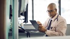 Healthcare provider at a desk scrolling through a tablet