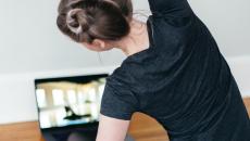A person following a video stretch routine on their laptop