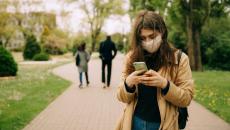 A person wearing mask is typing on their phone