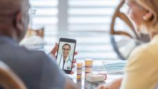 Two people on a telehealth call with medication on the table