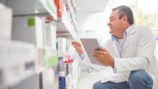 A pharmacist doing an inventory in a drug store using a digital tablet